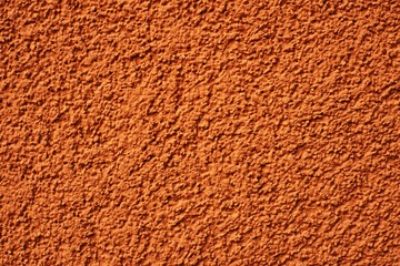 Home facade texture. Rough surface. Grunge grain. Crushed rocks in the wall. Exterior home decoration. Stucco wall pattern. Orange color retro design. Noisy design background.