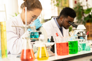 Group of Microbiologist Looking at a Lab-Grown Cultured Vegan Meat Sample in a Microscope. Medical Scientist Working on Plant-Based. medical biotechnology research laboratory using microscope.