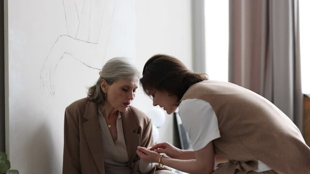 adult daughter shows old mother a new manicure at home