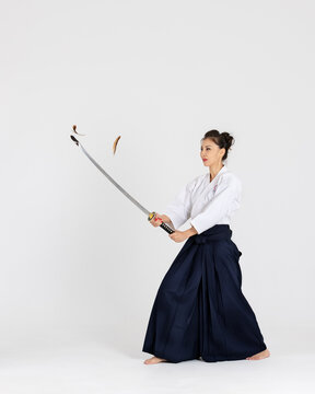 Aikido master woman in traditional samurai hakama kimono with black belt with sword, katana on white background. Healthy lifestyle and sports concept.