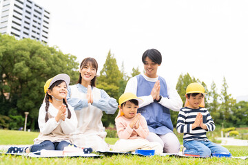 公園でお弁当を食べる保育士と園児