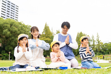 公園でお弁当を食べる保育士と園児