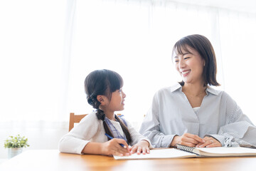 勉強する女の子と見守る母