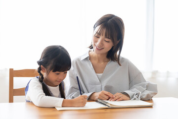 勉強する女の子と見守る母