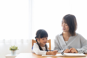 勉強する女の子と見守る母