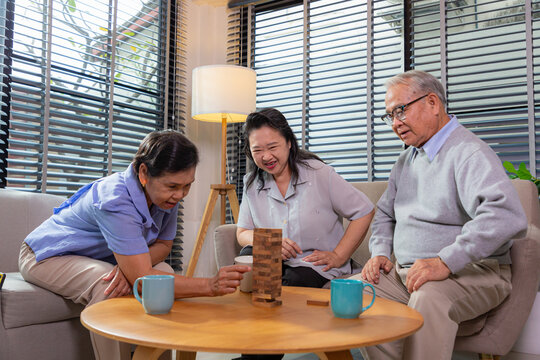 Elderly friends building tower from wooden cubes leisure time in nursing home.