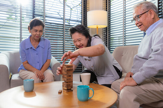Elderly friends building tower from wooden cubes leisure time in nursing home.