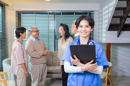 Young nurse in blue coat smiling looking at camera. Portrait of satisfied elderly patient and his caregiver. Medical care of older generation people, nursing concept