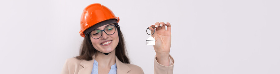 A girl in a construction helmet holds a house. Realtor on a white background.