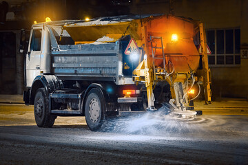 Truck spread salt and sand on snowy city road during blizzard at night shift, night work road...
