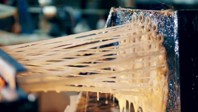 Strands of fiberglass covered in glue getting pulled together