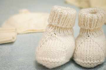 Fototapeta na wymiar Knitted children's shoes for a boy on a light background, close-up, children's shoes. Postcard.