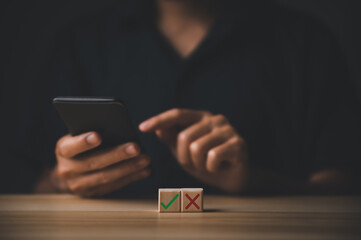 businessman and wooden block showing checks marks and wrong. The idea is to decide to vote. think yes or no
