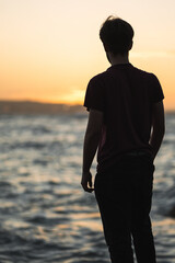 Hombre viendo el atardecer delante del mar