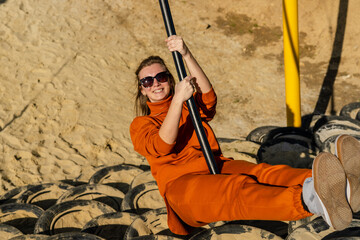 Smiling woman in sunglasses riding on a swing