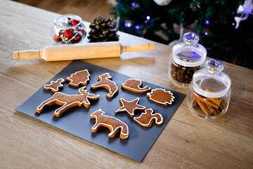 Ginger cookies and Christmas spices lie on the wooden table. The concept of the New Year and Christmas. Holiday atmosphere. Fir tree with fairy lights