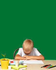 Boy hid his eyes. There are pencils, book, cubes, paints on table. Fatigue, training, coercion,...