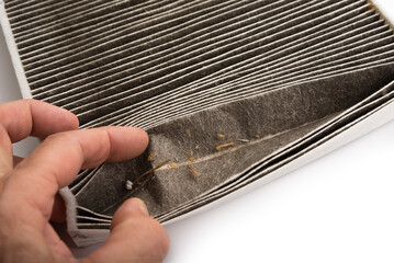 Dirty cabin filter open with a hand on a white