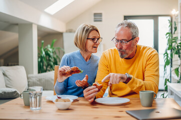 Senior couple eating breakfast at home and spending morning together