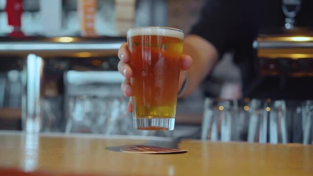 Medium shot of glass with beer at bar counter. Slow motion.