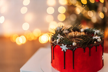 Christmas red cake covered with chocolate in front of the lights of the garlands.