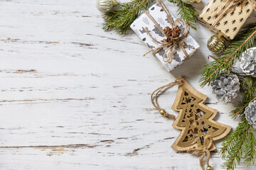 Christmas gold decor, fir tree twigs and gifts box on a white wood background. View from above. Copy space.