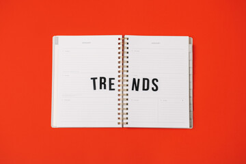 Global World Trends, Top New trends, forecasting. Word trends in open notepad planner on red background.