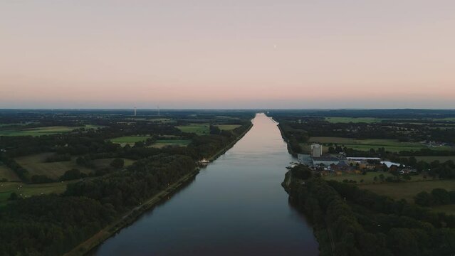 Aerial view of a river after sunset in the north of Germany. Moon and wind farms visible in the horizon
