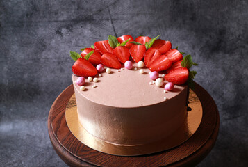 Delicious beautiful cake in chocolate glaze with strawberries and mint