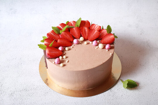 Delicious beautiful cake in chocolate glaze with strawberries and mint	
