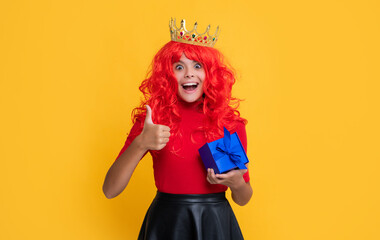 glad amazed child in diadem with present box on yellow background