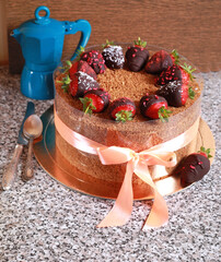 beautiful dessert is a delicious cake for the holiday decorated with chocolate-covered strawberries and a coffee pot on the table