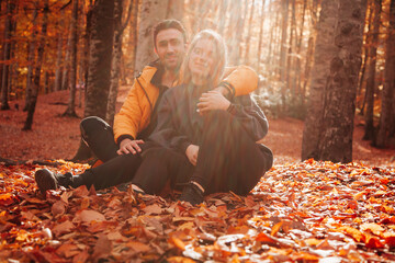 Fototapeta premium A couple sitting in the autumn forest. People in Autumn concept. 
