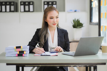 business woman or accountant who are using a calculator to calculate business data Accounting documents and laptop computer at the office business idea