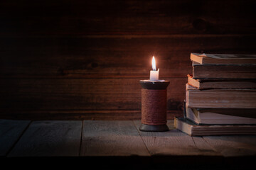 old books on a wooden desk and a burning candle, reading books concept, free space for text