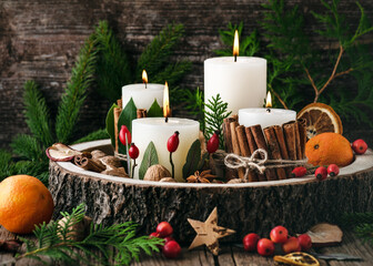 Christmas, advent wreath with four white burning candles decorated with natural material. Slices of...