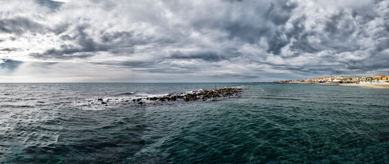 Panoramic view of bad weather and dramatic sky over Roman coast at Ostia Lido with city skyline and...