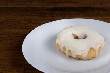 Sweet donuts with cream topping and powdered milk served on a plate. Close-up photo with empty space for texts on the left.