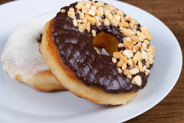 Sweet donuts with cream and powdered milk frosting and another donuts with chocolate and chestnut frosting. Food aligned left.