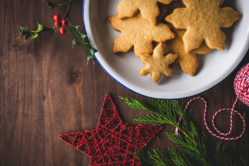galletas de Navidad en un plato de metal, junto a ramas de ciprés y acebo, adorno de estrella y...