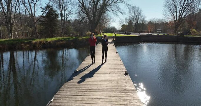 two women walking a Dock enjoying the Fall Season ,  walking towards Camera  (series)