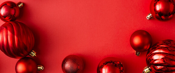 Banner made of Red Christmas balls decoration on red background. New Year greeting card. Minimal style. Flat lay, top view, copy space.