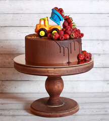Truck with fresh raspberries on a chocolate cake for children