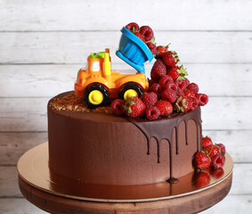 Truck with fresh raspberries on a chocolate cake for children