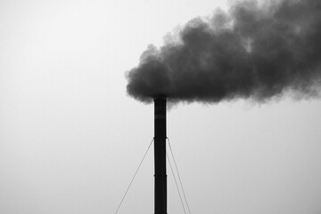 Grayscale shot of a factory emitting black toxic smoke