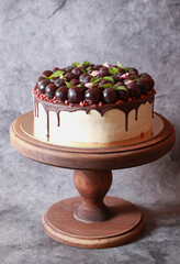 Delicious dessert cake with chocolate, grapes and mint on a wooden stand