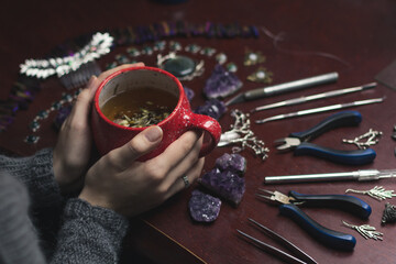 Close up hot beverage at work photo. Mug of warm tea. Refreshment. Side view photography with woman hands on background. High quality picture for wallpaper, travel blog, magazine, article