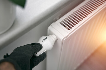 Increasing thermostat radiator value to warm up the home during cold weather. Concept of the cold temperature inside houses.