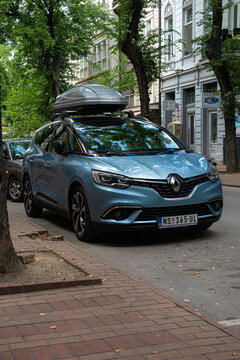 Light blue minivan Renault Grand Scenic 4th generation (2016) with roof rack box on it is parked in center of Subotica, Serbia, 25.08.2022. Vertical image