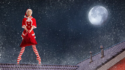 Dancing girl ballerina with a gift in her hands in a Santa Claus costume on the roof of a house on Christmas night against the background of the starry sky. © Maria Moroz